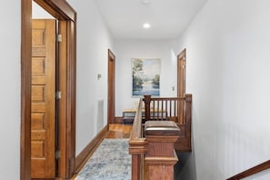 A hallway with wooden doors, a bench, and a painting on the wall.