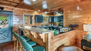 A wooden cabin interior with a kitchen, bar area, and seating.