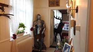 A narrow hallway with a knight's armor statue, a black horse statue, and a dining area in the background. - 2-person Room in a Hotel in Tranekaer (Tranekaer)