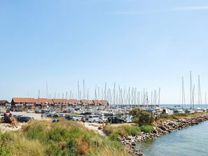 Un puerto deportivo con numerosos veleros amarrados a lo largo de una costa rocosa.