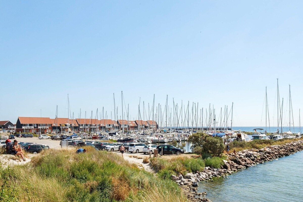 A marina with numerous sailboats docked along a rocky shoreline.