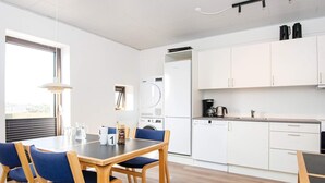A modern kitchen with white cabinets, a dishwasher, and a coffee maker. - Apartment in Holiday Park- Shared Kitchen (Ulfborg)
