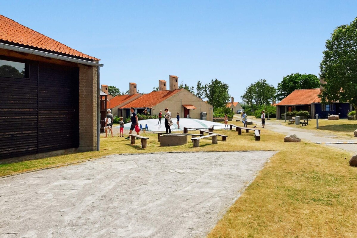 A courtyard with picnic tables, a playground, and a building with a red-tiled roof.