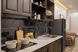Eine moderne Küche mit dunklen Schränken, einer Marmorarbeitsplatte, einem eingebauten Backofen und einem Kühlschrank.