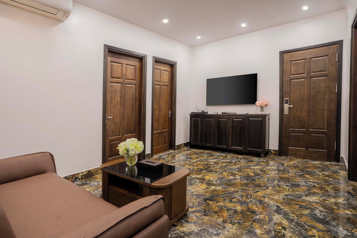 A spacious living area with a marble floor, a sofa, a coffee table, and a flat-screen TV mounted on the wall.