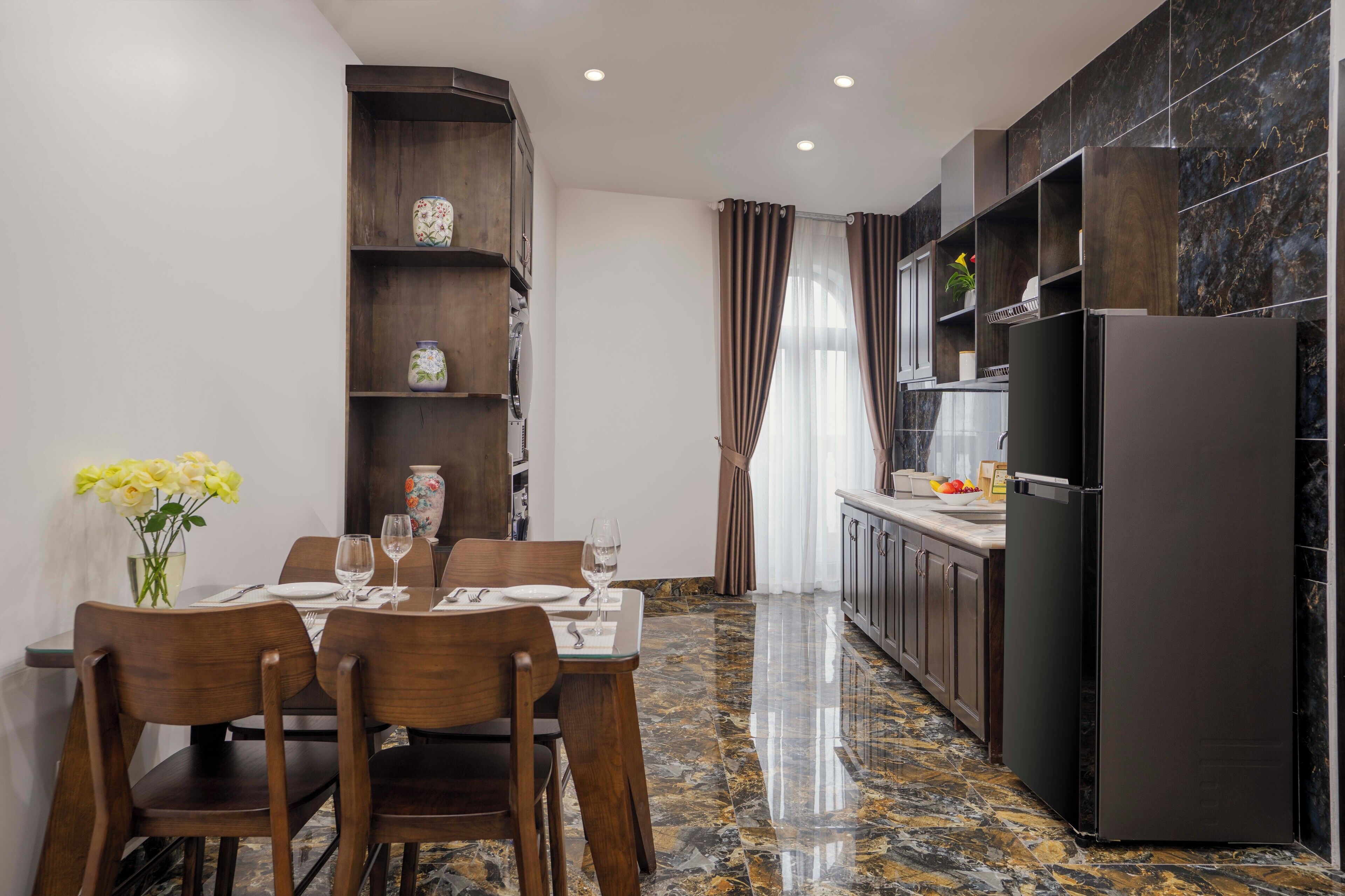 A modern kitchen with dark cabinetry, a marble countertop, and a built-in refrigerator.