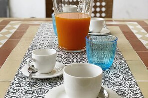 A table with a patterned tablecloth, a pitcher of orange juice, and white cups and saucers. - Sweet Sun Studio Apartment – Cozy Comfort Just Minutes from Sorrento ☀️🏡 (Meta)