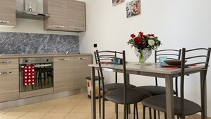 A modern kitchen with wooden cabinets, a built-in oven, and a dining table with chairs. - Sweet Sun Studio Apartment – Cozy Comfort Just Minutes from Sorrento ☀️🏡 (Meta)