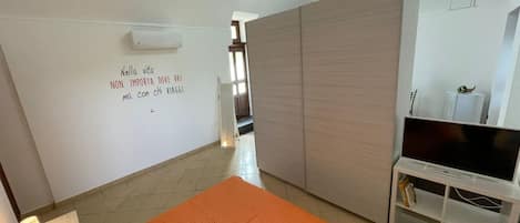 A bedroom with a bed, a TV stand, and a wardrobe.