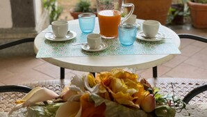 A round table with a patterned tablecloth, a pitcher of orange juice, and several cups and saucers. - Sweet Sun Studio Apartment – Cozy Comfort Just Minutes from Sorrento ☀️🏡 (Meta)