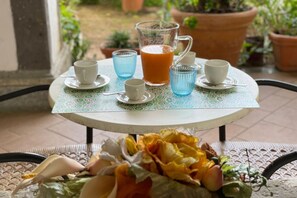 A round table with a patterned tablecloth, a pitcher of orange juice, and several cups and saucers. - Sweet Sun Studio Apartment – Cozy Comfort Just Minutes from Sorrento ☀️🏡 (Meta)