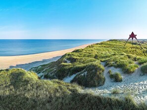 A beach with a dune and a red structure on top. - 10 Person Holiday Park Home in Ulfborg (Ulfborg)