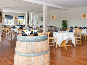 A restaurant with wooden tables, chairs, and a barrel of wine bottles. - 10 Person Holiday Park Home in Ulfborg (Ulfborg)