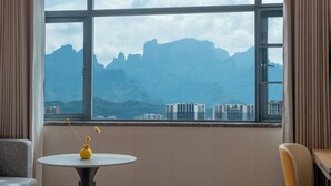 A room with a large window offering a view of mountains and buildings. - Zhangjiajie Homeinn Plus Hotel (Zhangjiajie)