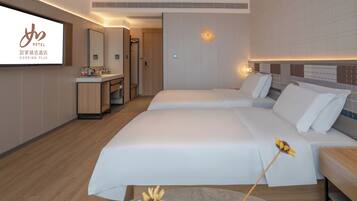 Habitación de hotel con dos camas, baño y un televisor que muestra el logotipo del hotel.