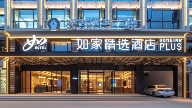 A hotel entrance with a car parked in front, glass doors, and illuminated signage. - Zhangjiajie Homeinn Plus Hotel (Zhangjiajie)