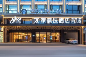 A hotel entrance with a car parked in front, glass doors, and illuminated signage. - Zhangjiajie Homeinn Plus Hotel (Zhangjiajie)