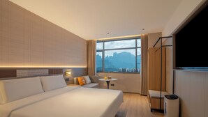 A modern hotel room with a large bed, a small table with a lamp, a TV, and a view of mountains through the window. - Zhangjiajie Homeinn Plus Hotel (Zhangjiajie)