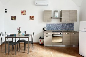 Eine kompakte Küche mit Essbereich, mit Marmor-Spritzschutz, Edelstahlgeräten und hellem Holzkorpus.