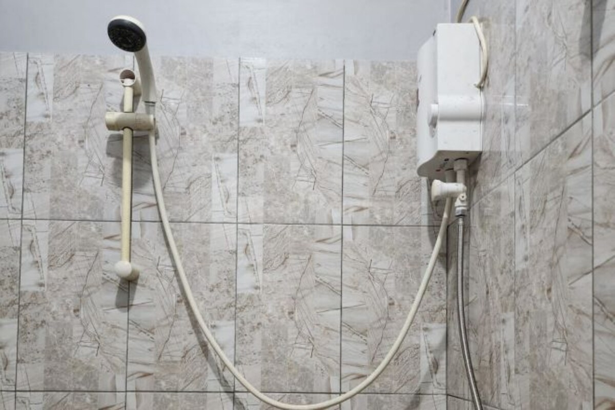 A shower with a handheld showerhead and a wall-mounted control unit.