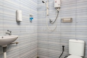 A bathroom with striped tiles, a sink, a toilet, and a shower. - Puspita Homestay Mitra RedDoorz (Pondok Melati)