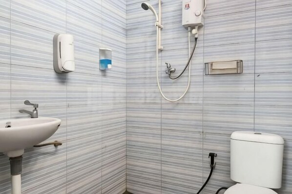 A bathroom with striped tiles, a sink, a toilet, and a shower. - Puspita Homestay Mitra RedDoorz (Pondok Melati)