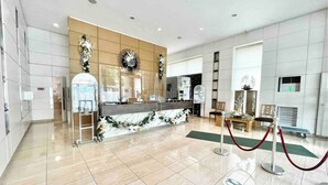 A modern reception area with a marble counter, a sunburst wall decoration, and a security control kiosk. - Comfy condo. Best location on Shaw Blvd, front of Shang Mall. Short walk to SM. (Mandaluyong City)