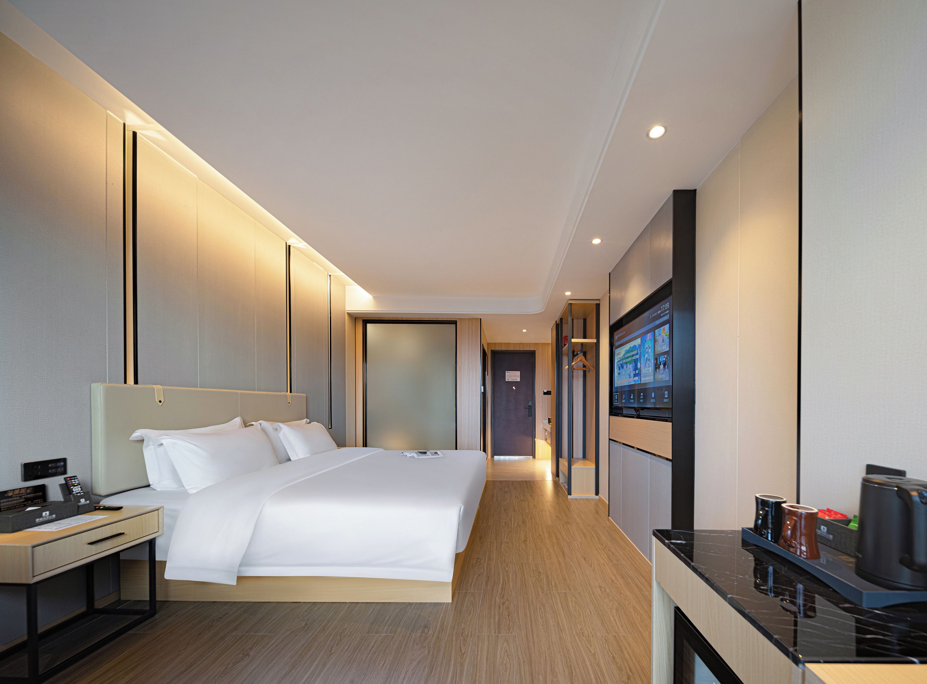 Una habitación de hotel moderna con una cama grande, mesitas de noche, un televisor de pantalla plana y una cafetera.