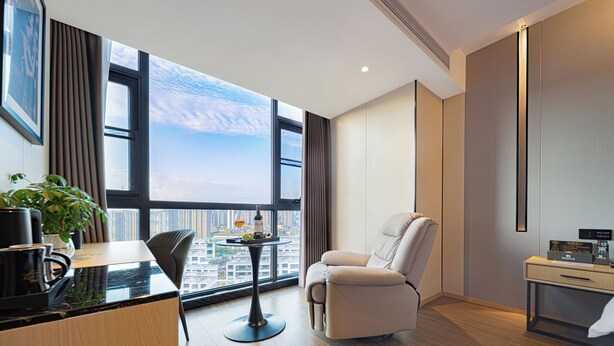 A modern hotel room with a large window, a dining table, a sofa, and a small desk. - Zhangjiajie Hero Boutique Hotel (Zhangjiajie)