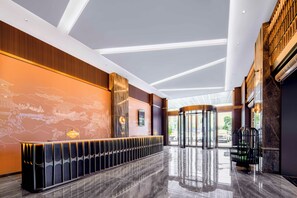 Um lobby moderno com um balcão de recepção, uma tela digital e uma porta giratória.