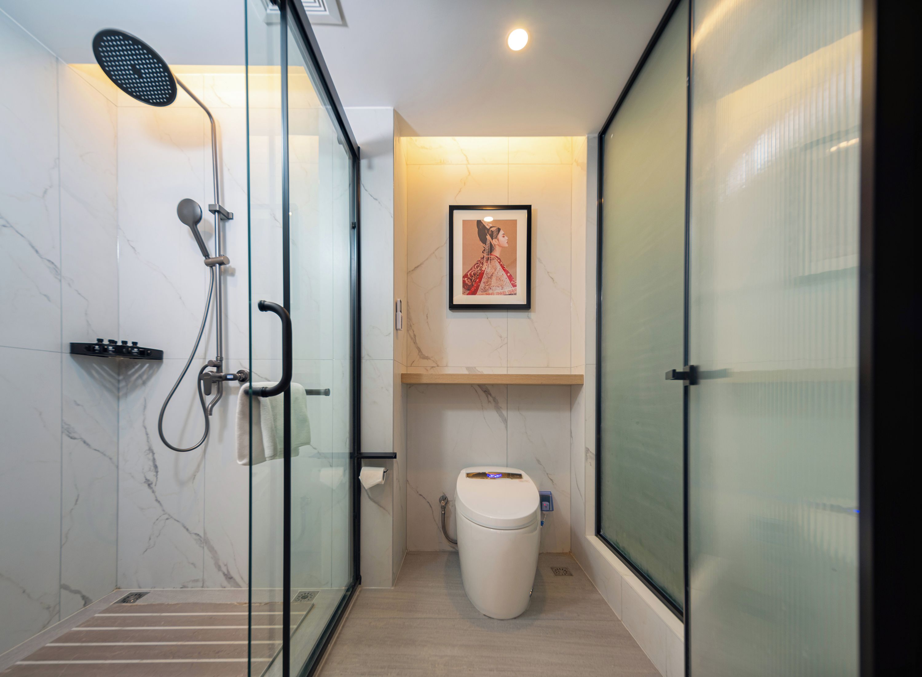 Ein modernes Badezimmer mit einer Duschkabine, einer Toilette und einem gerahmten Bild an der Wand.