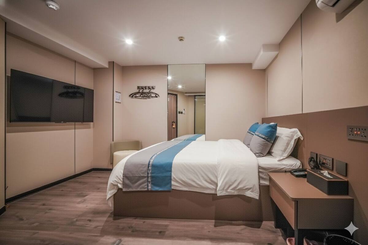 A modern hotel room with a large bed, a desk, a flat-screen TV, and a mirror.
