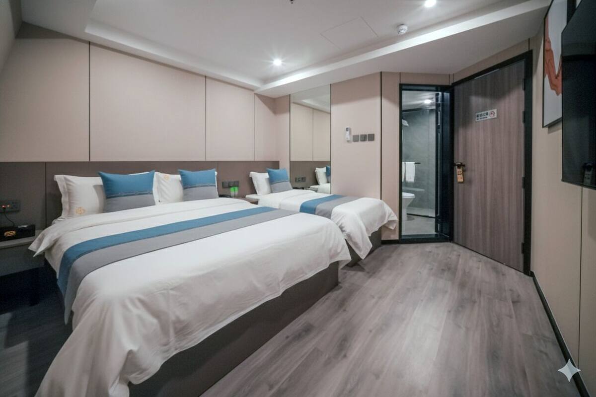 A hotel room with two beds, a wardrobe, and a bathroom.