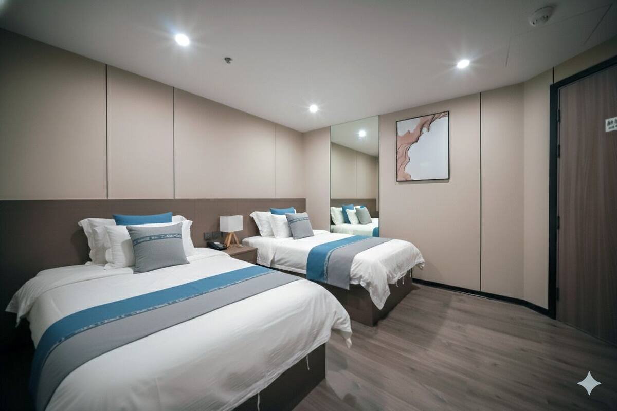 A hotel room with two beds, a large mirror, and a wooden floor.