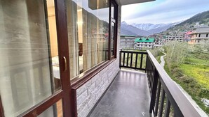 Un balcon offrant une vue sur un paysage montagneux, un chemin pavé et des bâtiments dotés de toits végétalisés.