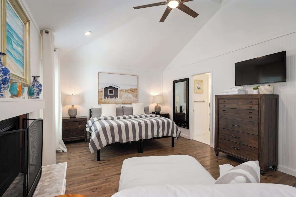 A bedroom with a bed, a dresser, a television, and artwork on the walls.