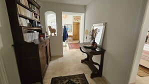 A hallway with a bookshelf, a console table with a vase, and a rug. - Master villa for 14 people with air conditioning (LES ISSAMBRES)