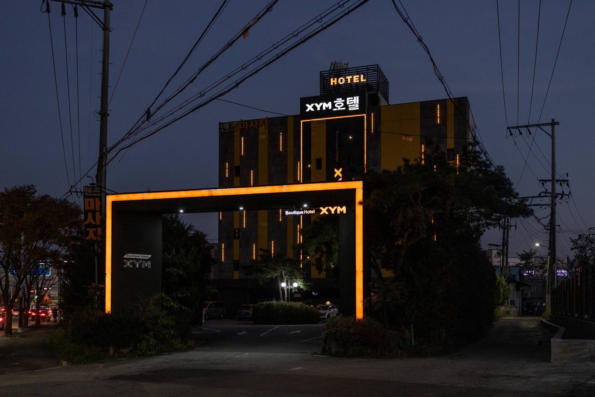 A modern hotel with a prominent entrance archway and signage indicating it is the Boutique Hotel XYM.