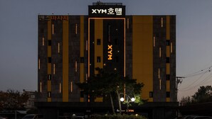 Moderni rakennus, jossa on selkeästi näkyvässä paikassa suuri ”XYM”-kyltti. Rakennuksessa on pystysuuntaisia valonauhoja ja keskellä vielä yksi pystysuuntainen valonauha.