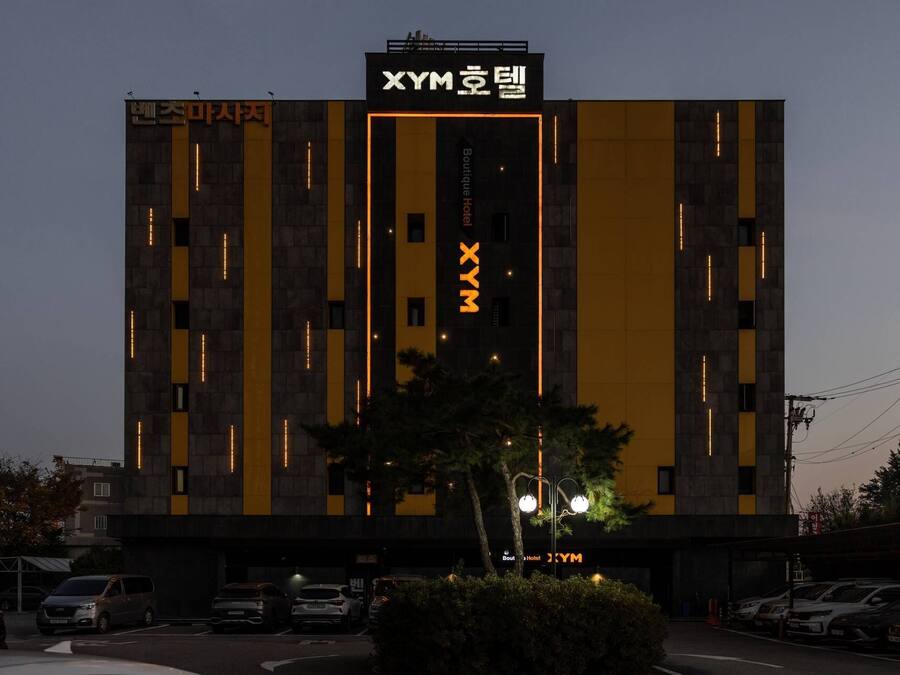 A modern building with a prominent 'XYM' sign, featuring vertical light strips and a central vertical light strip.