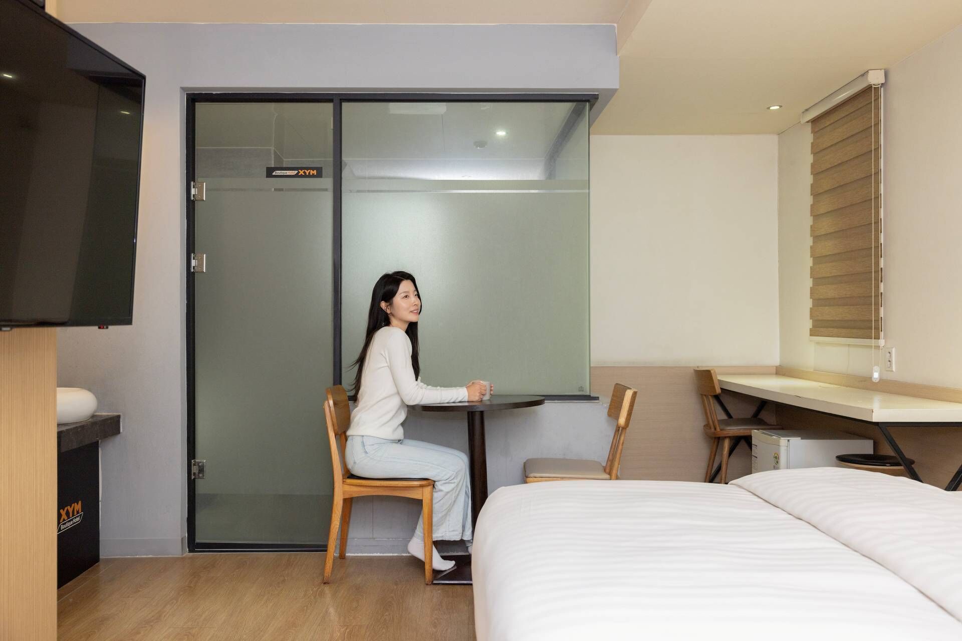 A hotel room with a bed, a desk, a chair, and a sliding door closet.