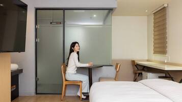 A hotel room with a bed, a desk, a chair, and a sliding door closet.