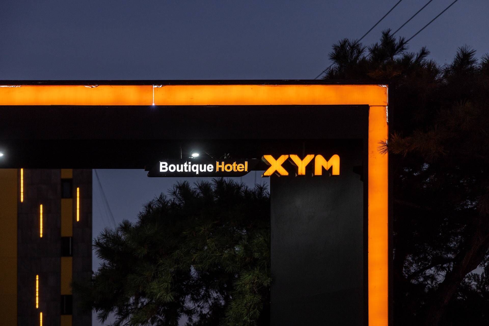 Een hotelentree met een bord waarop 'Boutique Hotel XYM' staat.