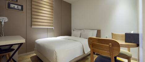 Un dormitorio con cama, escritorio, silla y ventana con persianas.