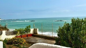 Une vue sur l’océan depuis un balcon doté d’une rambarde en treillis, d’un sol en béton et de quelques plantes.