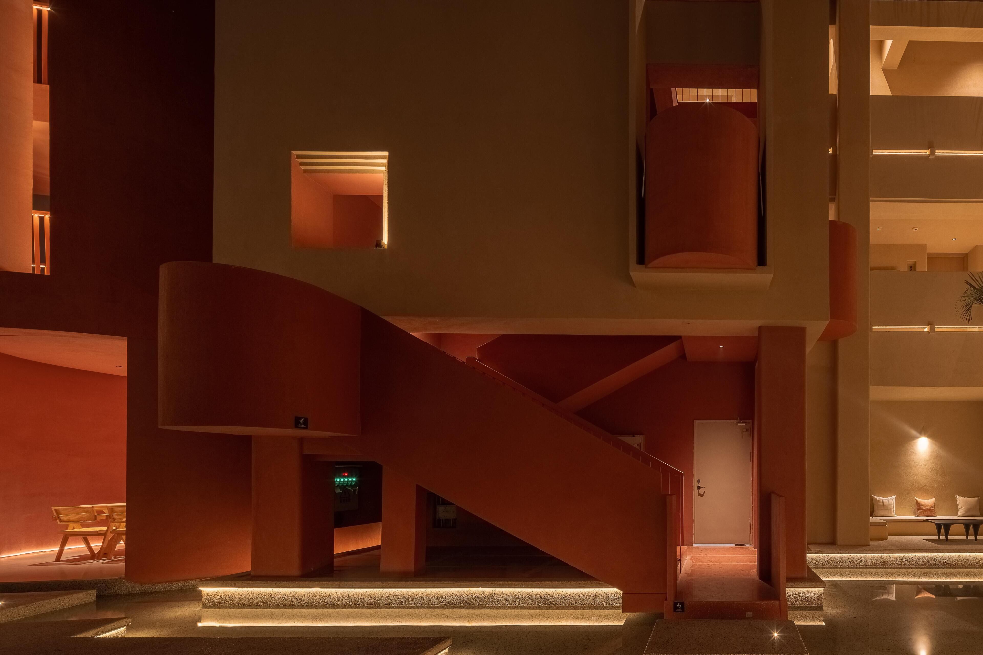A modern interior with a staircase, a bench, and a seating area with a plant.