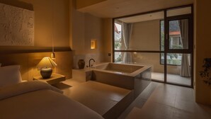 A modern bathroom with a large bathtub, a vanity with a mirror, and a wall-mounted light fixture.