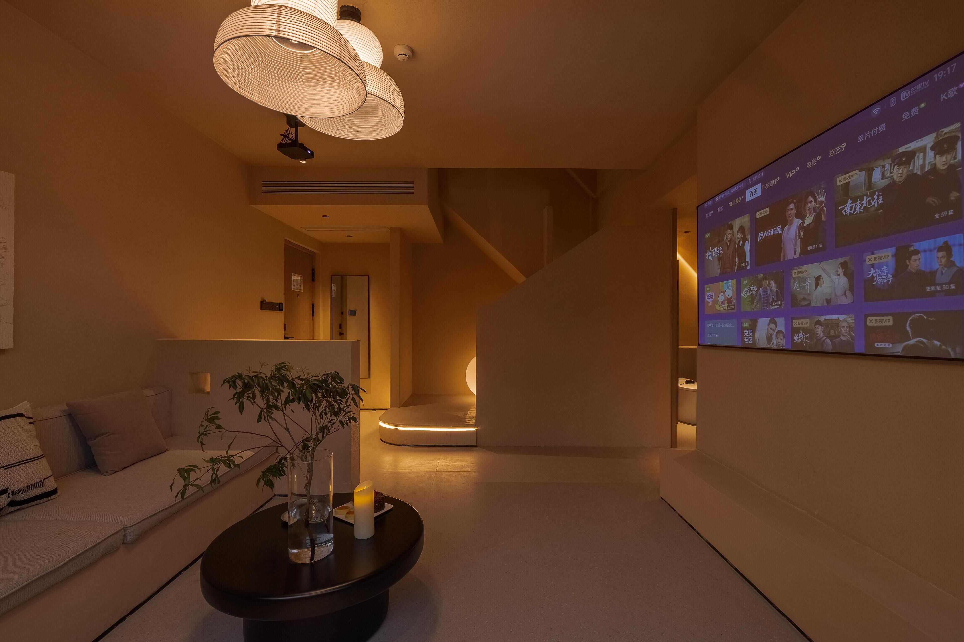 A modern interior with a sofa, a coffee table, and a wall-mounted screen displaying content.