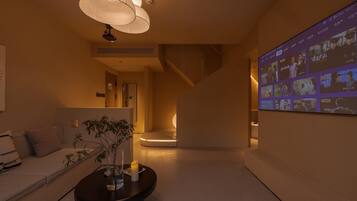 A modern interior with a sofa, a coffee table, and a wall-mounted screen displaying content.