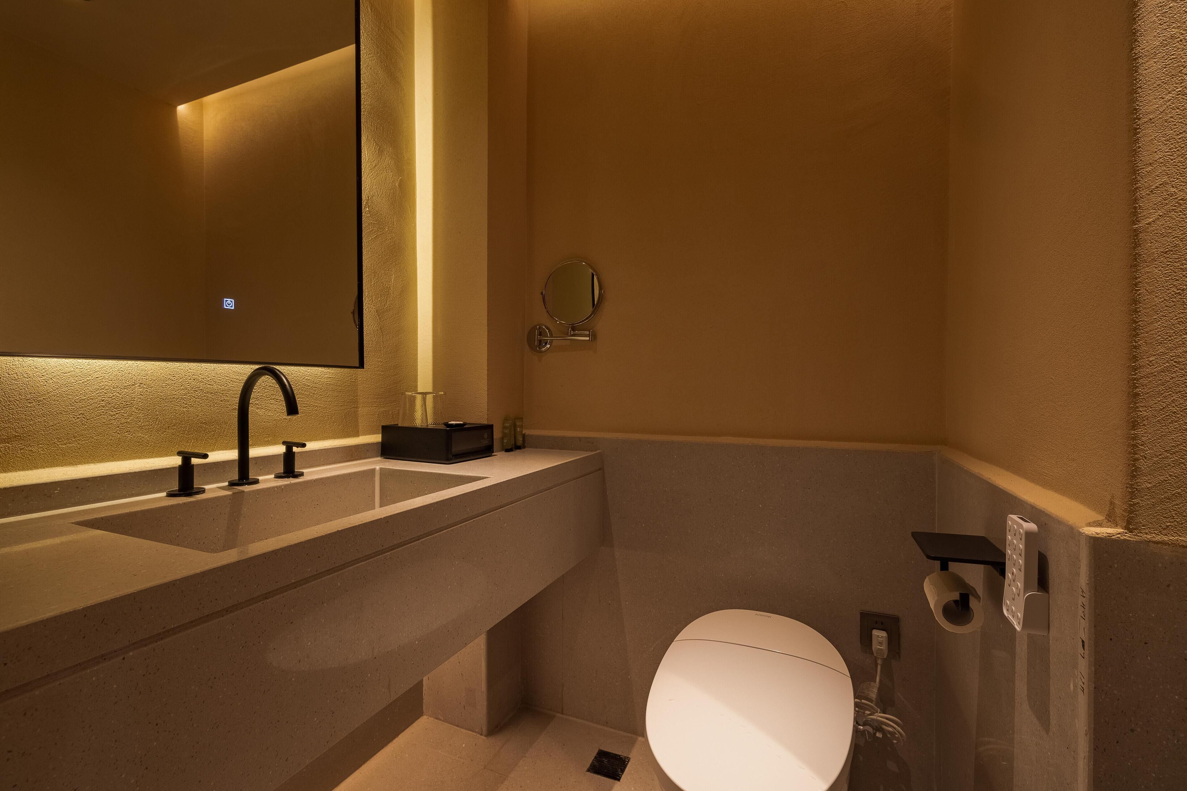 A modern bathroom with a large mirror, a sink, and a toilet.